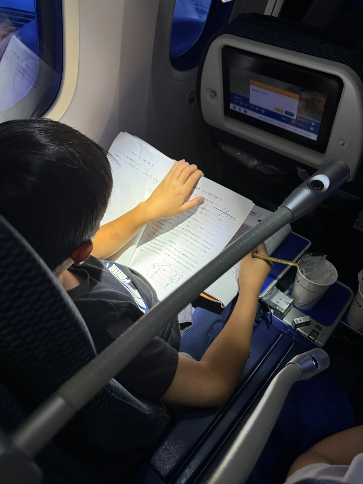 ANAプレミアムエコノミーの座席で教材を広げて勉強する子ども