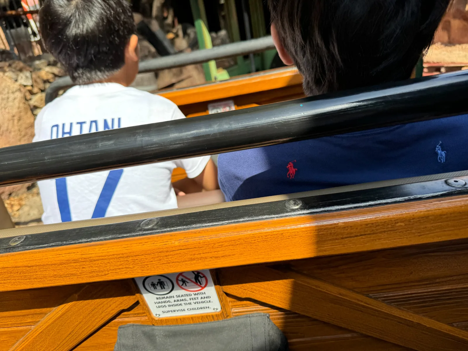 ディズニーランドのアトラクション車両に乗る子どもたちの後ろ姿